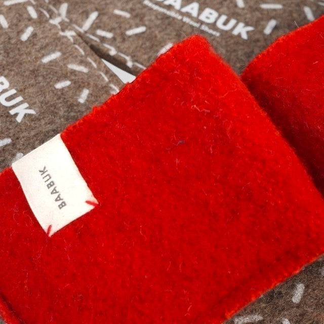 Baabuk Baabulette wool slide sandals in Swiss red with a branded fabric label, showing textured wool construction.