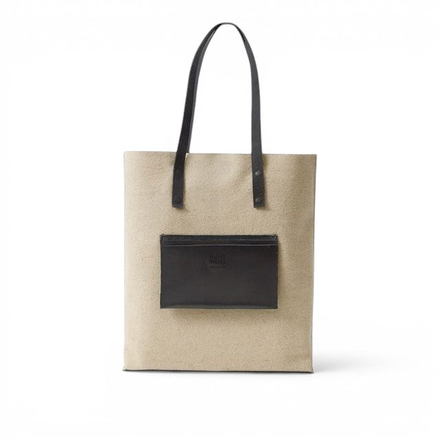 Baabuk Blacknose tote bag in beige wool with black leather handles and a front pocket on a white background.
