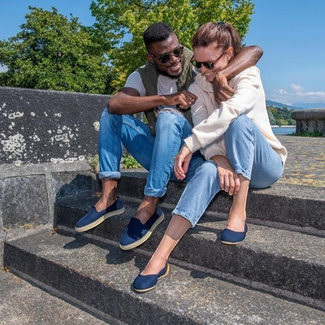 Baabuk blue wool ballerina shoes worn by a woman sitting on stone steps next to a man outdoors.