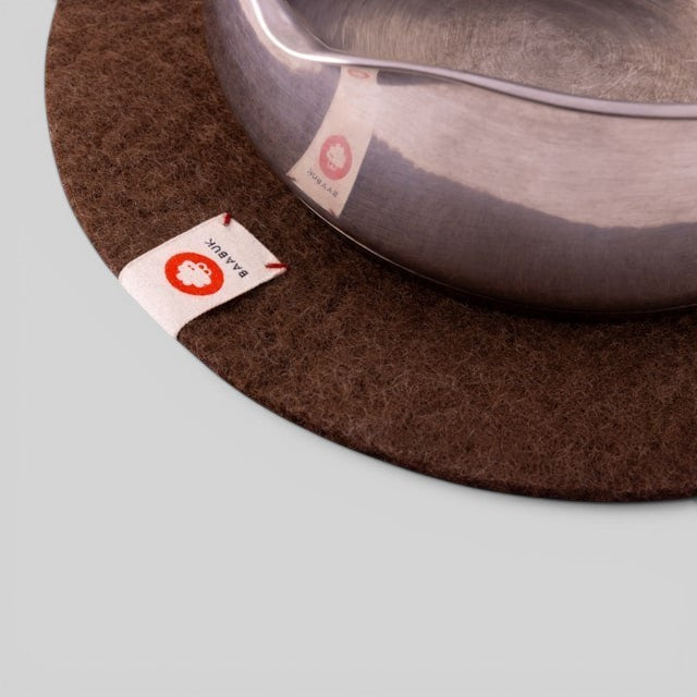 Baabuk brown felted wool trivet hot plate with a small leather strap detail under a metal pot