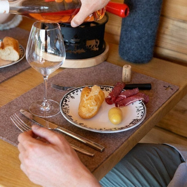 Baabuk brown felted wool table mat on a wooden dining table with a plate of food and wine glass