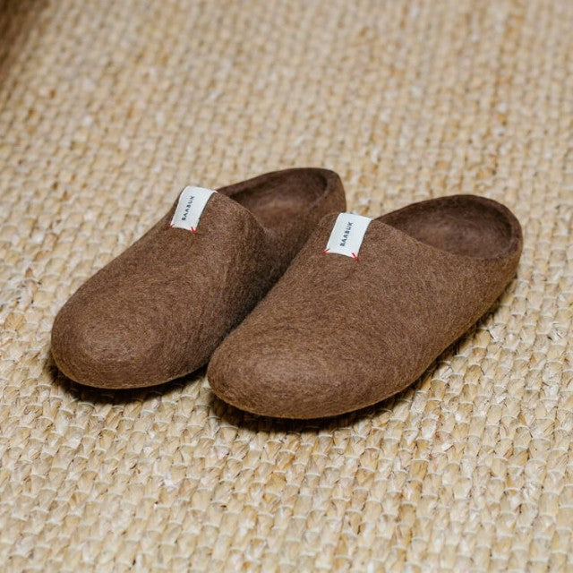 Baabuk brown wool Kanga slippers with a minimalist slip-on design and white brand tag on a woven textured surface.