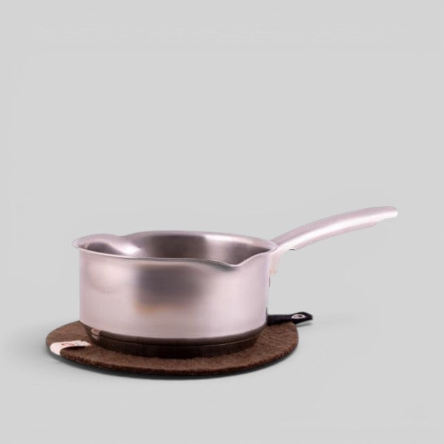 Baabuk brown felted wool trivet hot plate with a leather strap under a stainless steel saucepan