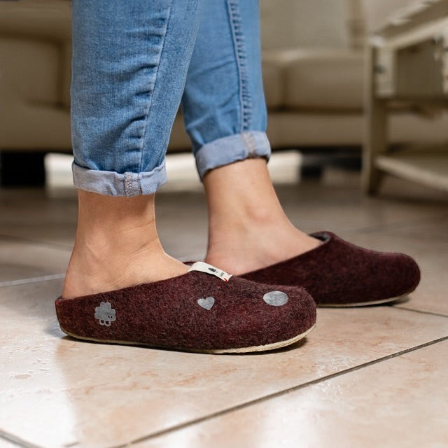 Baabuk wool slippers in dark burgundy with decorative patches worn on tiled floor with blue jeans