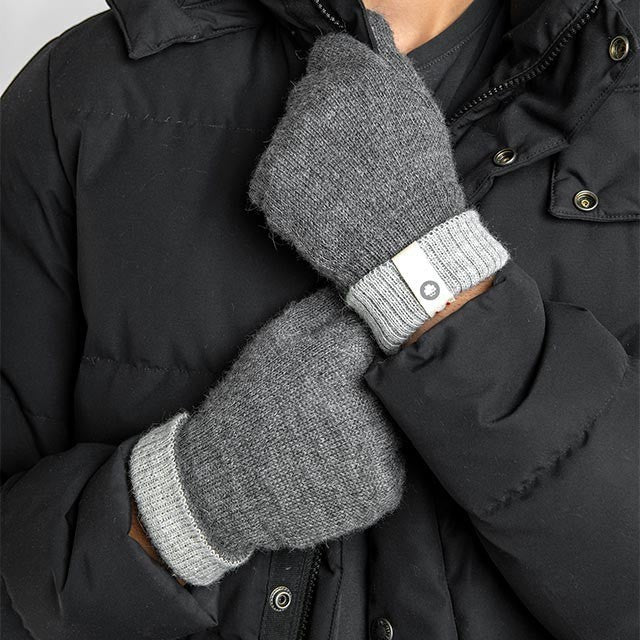 Baabuk dark grey baby alpaca wool gloves with ribbed cuffs worn by a person in a black winter jacket.