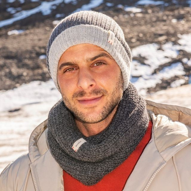 Baabuk dark grey baby alpaca wool infinity scarf worn by a man in a winter setting with a matching ribbed beanie