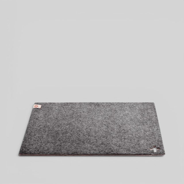 Baabuk dark grey felted wool table mat with a small Swiss cross cutout detail on a neutral background.