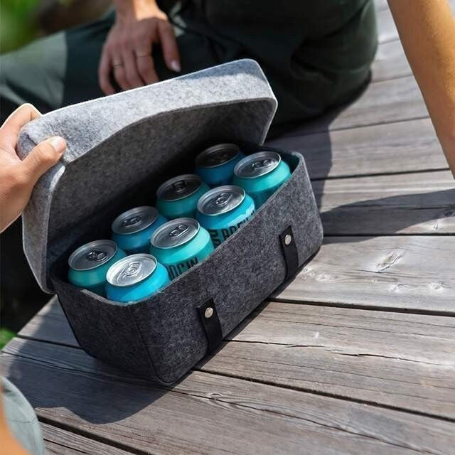 Baabuk dark grey wool beer cooler filled with chilled cans on a wooden deck