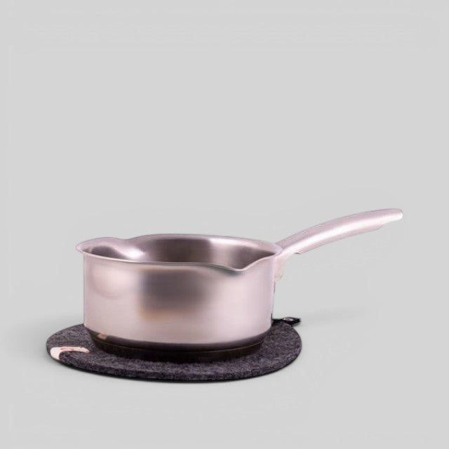 Baabuk dark grey felted wool trivet hot plate with a leather strap under a stainless steel saucepan