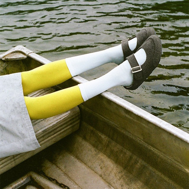 Baabuk grey wool Mary Jane sandals with adjustable buckle strap worn with white socks and yellow tights in a boat