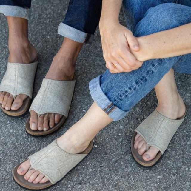 Baabuk Izard sandals featuring beige Pyrenean wool uppers and cork footbeds worn by two people on a paved surface.