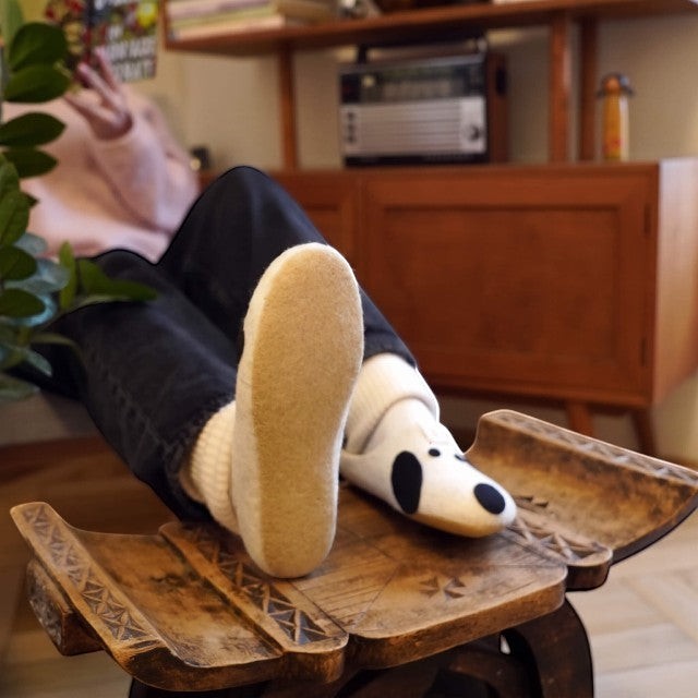 Baabuk Kanga Woof slippers in white wool with dog-inspired black spots and natural latex soles worn by a person