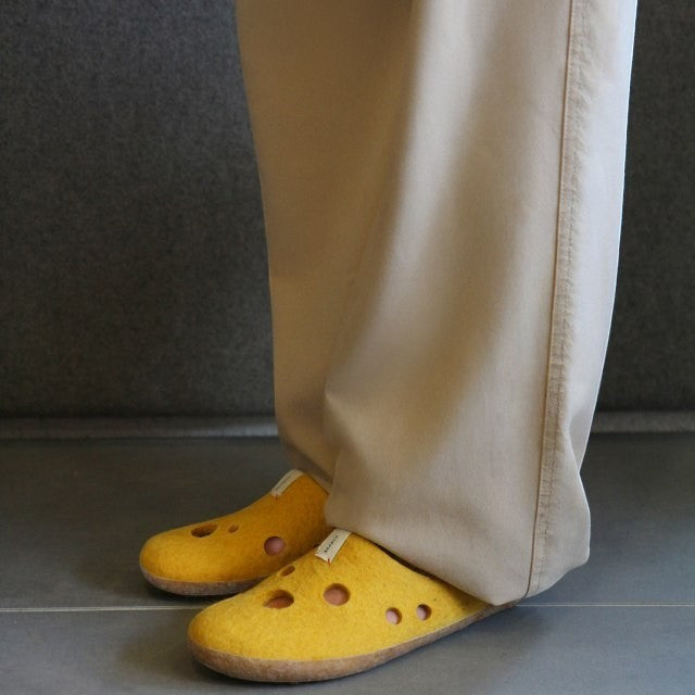 Baabuk Kanga slippers in yellow wool with Swiss cheese hole pattern worn with beige trousers