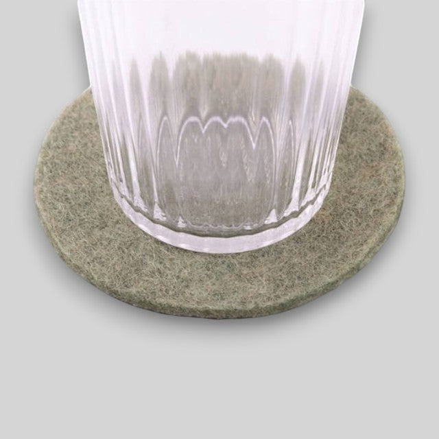 Baabuk khaki felt coaster made from 100% natural wool, shown under a clear glass on a neutral background.