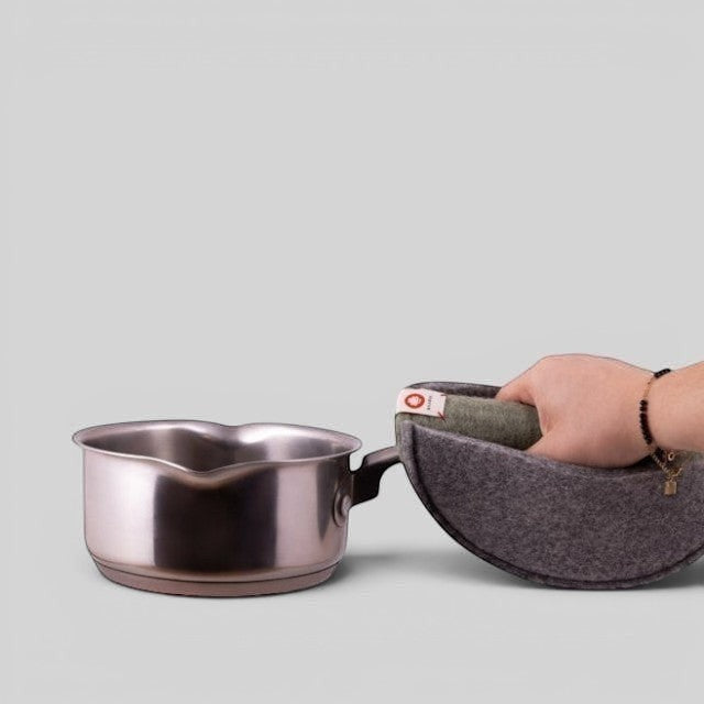 Baabuk khaki felted wool potholder with leather strap gripping a stainless steel saucepan