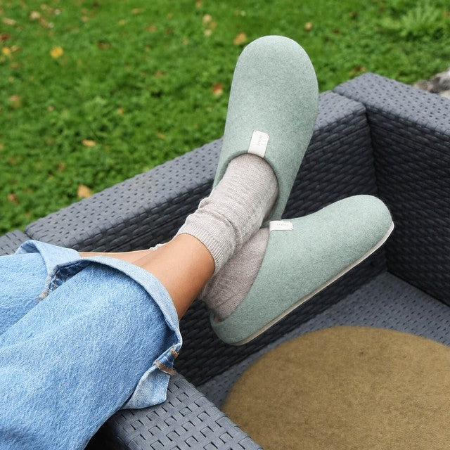 Baabuk light blue handfelted wool slippers with orthopedic cork soles worn outdoors with beige socks and blue jeans.