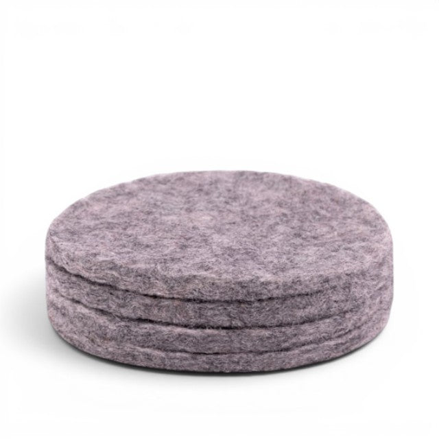 Baabuk set of four round light grey felt coasters made from 100% natural wool for furniture protection.