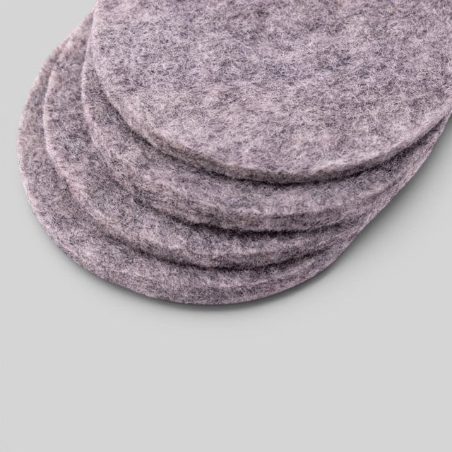 Baabuk set of four light grey circular felt coasters made from 100% natural wool for furniture protection.