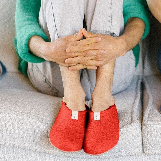 Baabuk Mel salsa red wool slippers with natural crepe rubber soles worn by a person sitting on a sofa