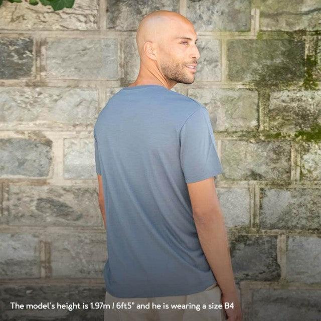 Baabuk dark grey merino wool T-shirt worn by a man standing against a stone wall, 10-year anniversary edition.