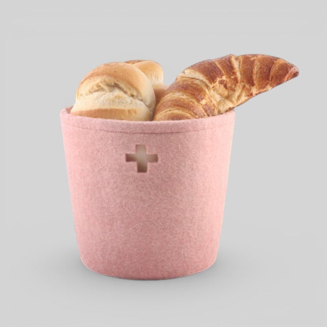 Baabuk small pink felted wool basket with a Swiss cross cutout, holding bread rolls and a croissant.