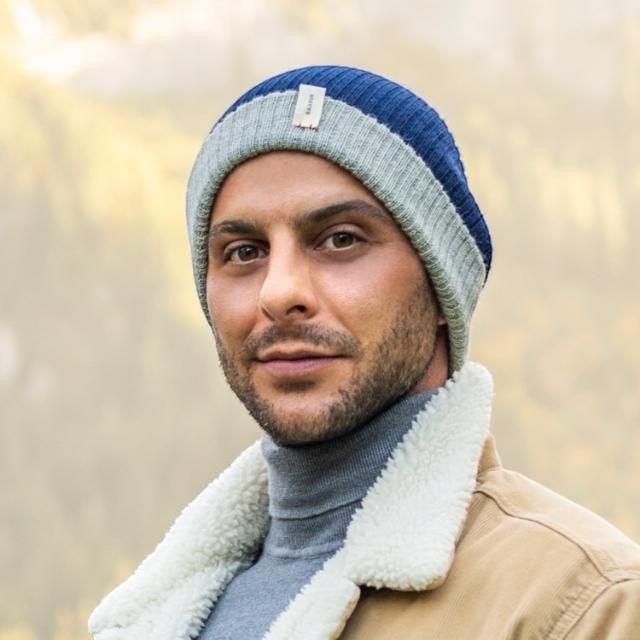 Baabuk reversible marine blue and grey baby alpaca wool beanie worn by a man in a winter jacket