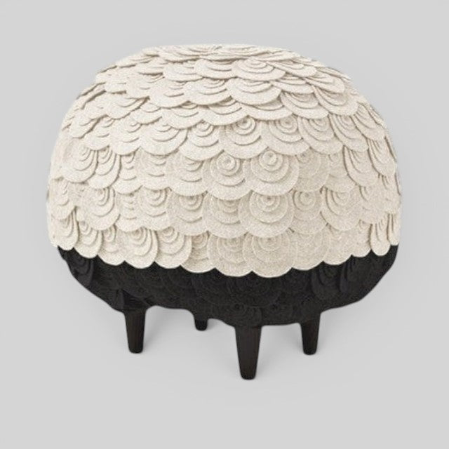 Baabuk Sheep Stool featuring cream-colored wool layers over a black felt body with four sturdy wooden legs.