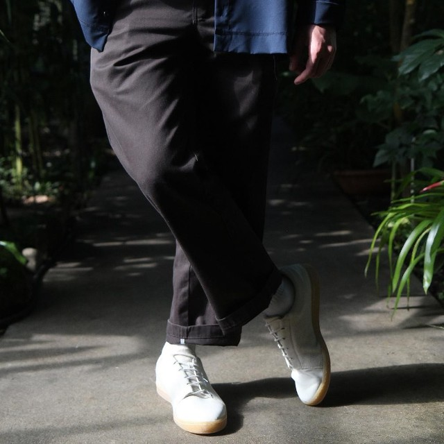 Baabuk Shunya Wooler white sustainable sneakers worn with dark trousers in a garden setting