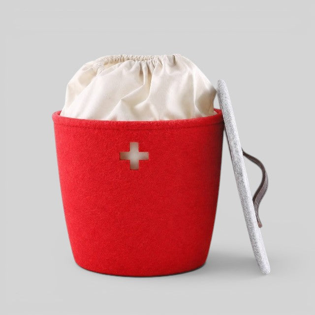 Baabuk small red felted wool basket with a Swiss cross cutout, white fabric liner, and a grey lid with leather strap.
