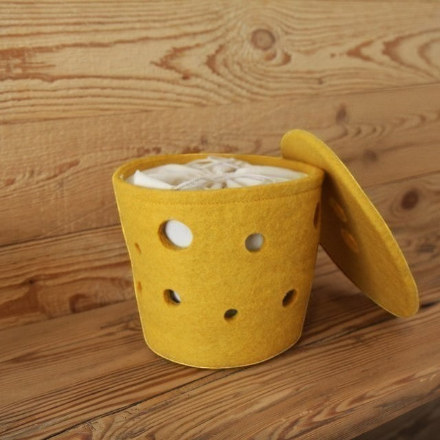 Baabuk Swiss Cheese small felted wool basket in yellow with circular cutouts and a matching lid on a wooden surface.