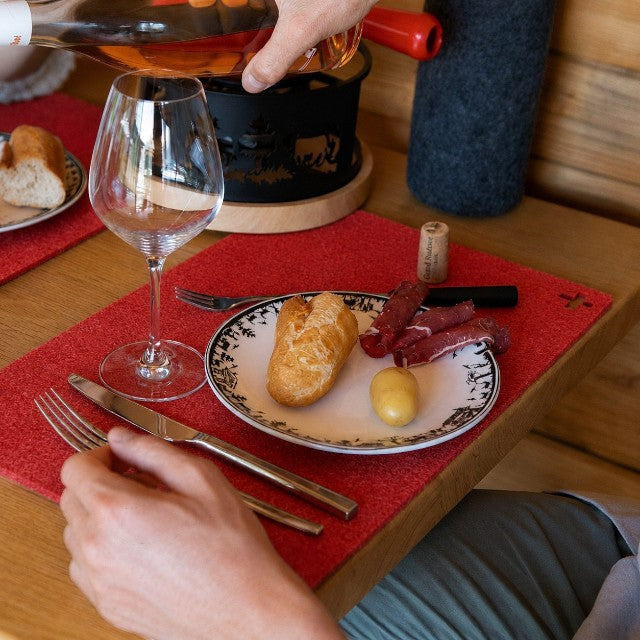 Baabuk Swiss red felted wool table mat on a wooden dining table with wine and food