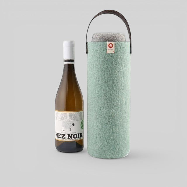 Baabuk turquoise wool wine cooler with a brown leather strap, shown next to a bottle of white wine.