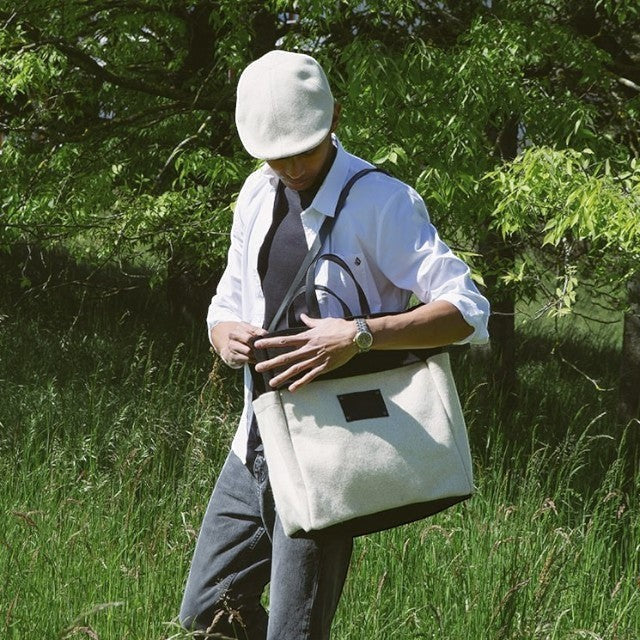 Baabuk wool beret in off-white, inspired by traditional Portuguese shepherd hats, worn by a man in a garden.