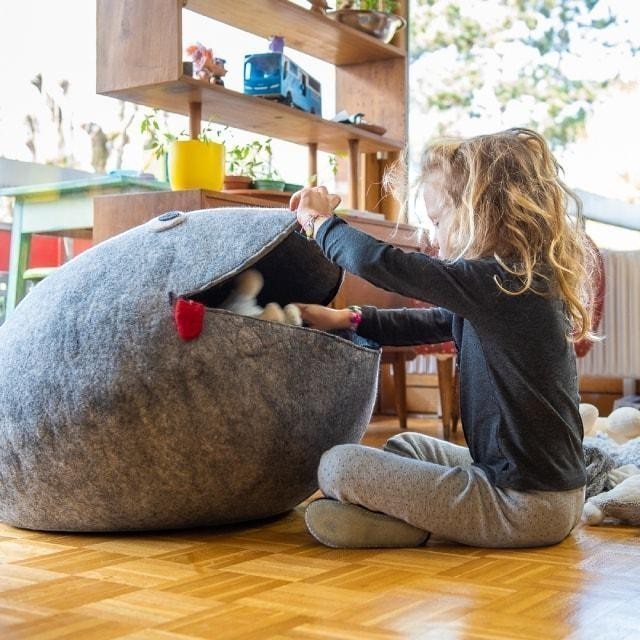 Child playing with a grey Baabuk wool frog storage basket in a bright living room
